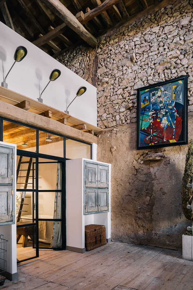 Entrada al despacho dentro de un salón rústico con muebles de madera, sofás cómodos y arte colorido en las paredes. Ambiente cálido y ecléctico