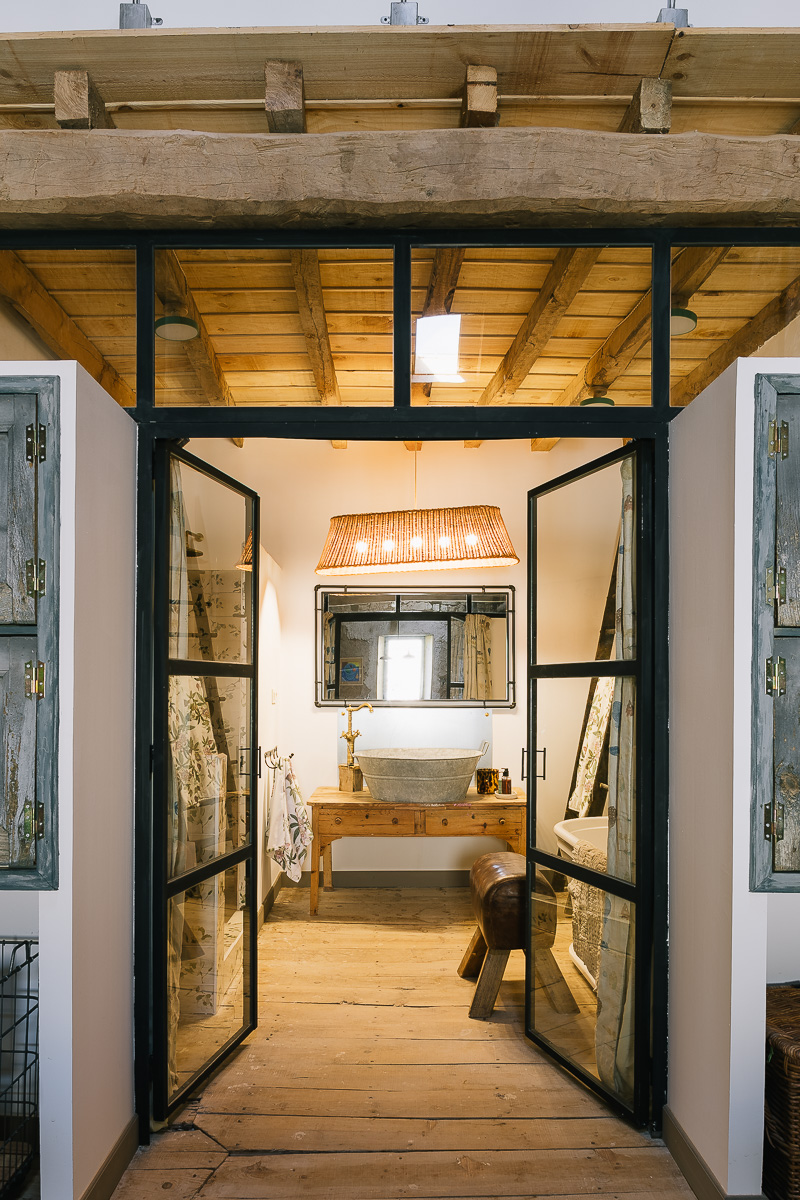 Baño con ducha en casa rural con detalles rúticos y antiguos.