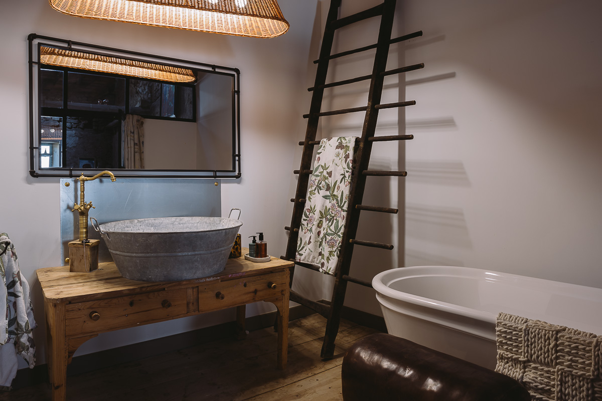 Baño con bañera en casa rural con detalles rúticos y antiguos.