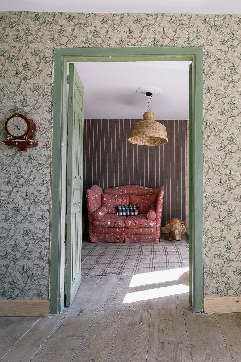 Sala de estar, con sofa rojo. Sala de estar rústica con muebles de madera, sofás cómodos y arte colorido en las paredes. Ambiente cálido y ecléctico.