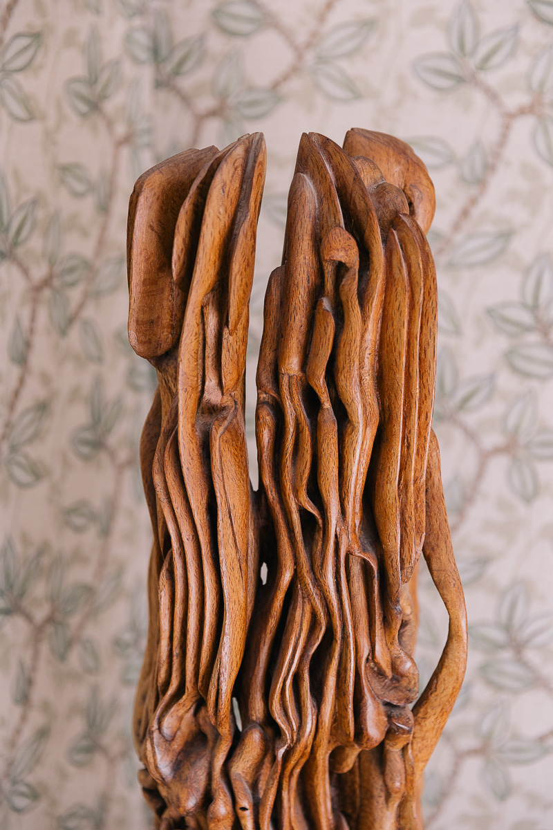 Detalle escultura madera sobre papel pintado con motivos de hojas verdes